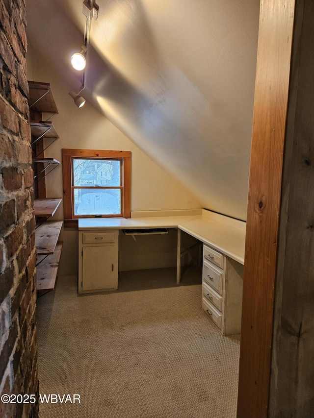 unfurnished office featuring carpet, lofted ceiling, and built in desk