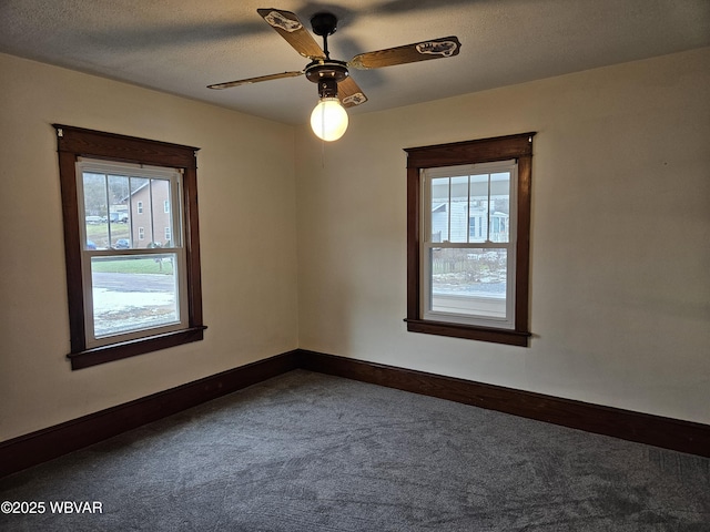 carpeted empty room with ceiling fan, a textured ceiling, and a wealth of natural light