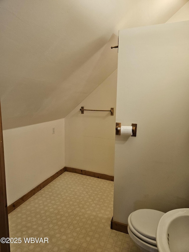 bathroom with toilet, sink, and vaulted ceiling