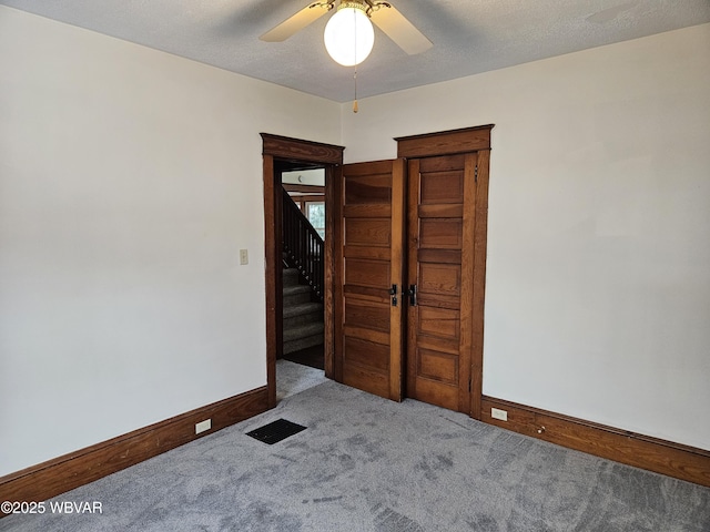 carpeted empty room featuring ceiling fan and a textured ceiling