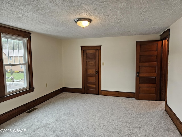 carpeted empty room with a textured ceiling