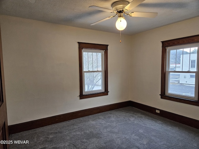 empty room with ceiling fan, dark carpet, and a textured ceiling