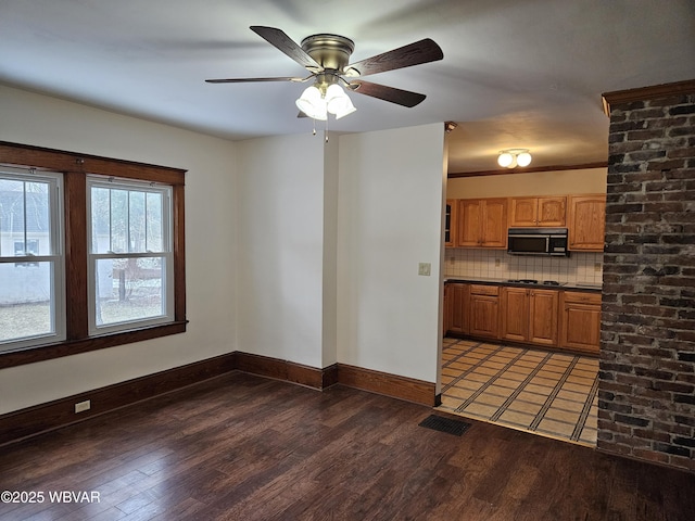 kitchen featuring black appliances, decorative backsplash, ceiling fan, and dark hardwood / wood-style flooring