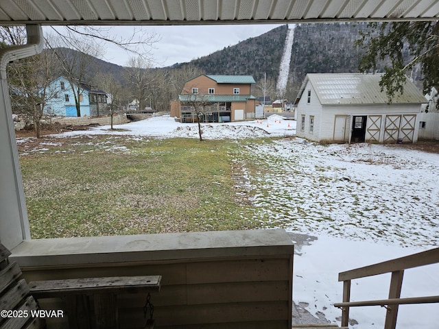 yard layered in snow with a mountain view and an outbuilding