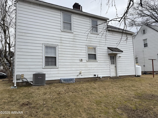 back of property with a yard, a chimney, and cooling unit