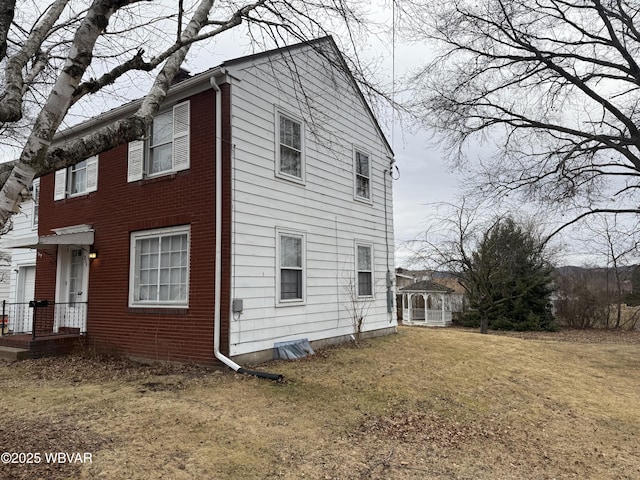 view of home's exterior with brick siding and a yard