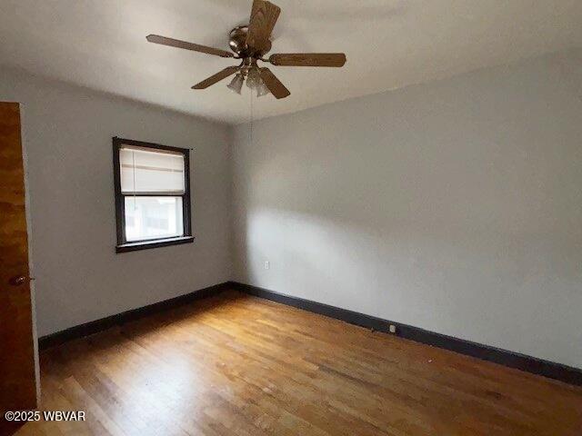 unfurnished room featuring ceiling fan, wood finished floors, and baseboards