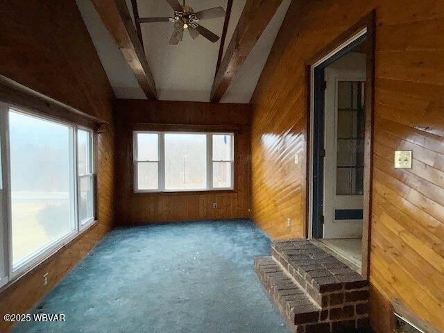 unfurnished sunroom featuring a ceiling fan and beamed ceiling