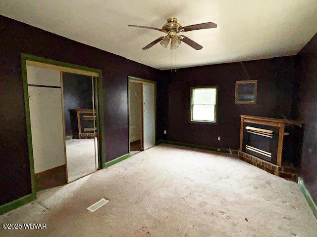 unfurnished living room with carpet floors, ceiling fan, a fireplace, and baseboards