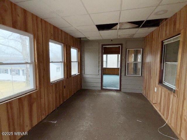 empty room with wood walls and a drop ceiling