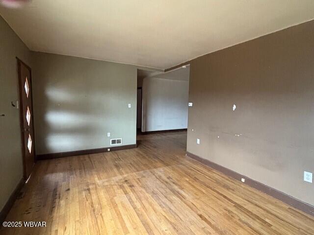 unfurnished room featuring visible vents, baseboards, and wood finished floors