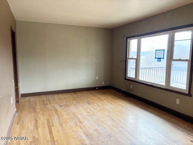 unfurnished room with baseboards and light wood-style floors