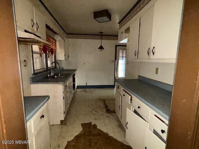 kitchen with dark countertops, white cabinets, a sink, and decorative light fixtures