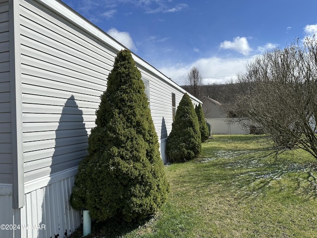 view of side of home featuring fence and a lawn