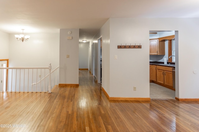 hallway with wood-type flooring, sink, and an inviting chandelier