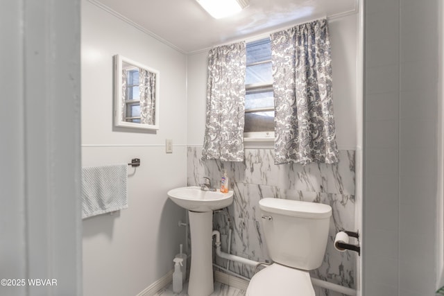 bathroom with toilet, crown molding, and tile walls