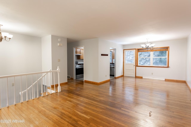 spare room with hardwood / wood-style floors, a baseboard heating unit, and a notable chandelier