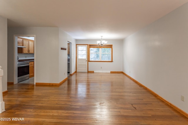 spare room with a notable chandelier, hardwood / wood-style flooring, and a baseboard radiator