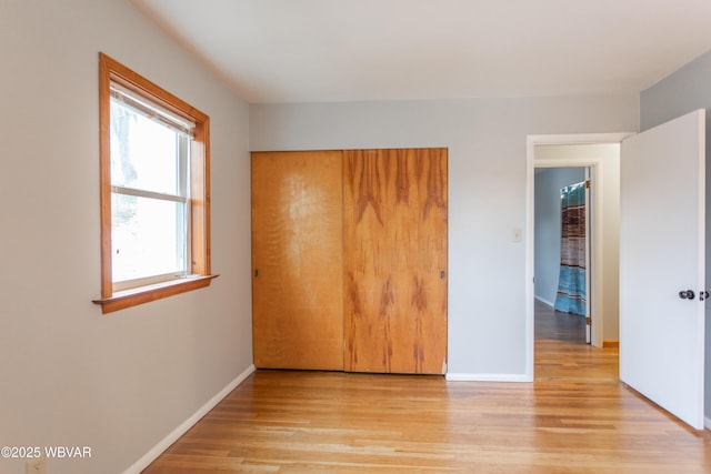 unfurnished bedroom with light wood-type flooring and a closet