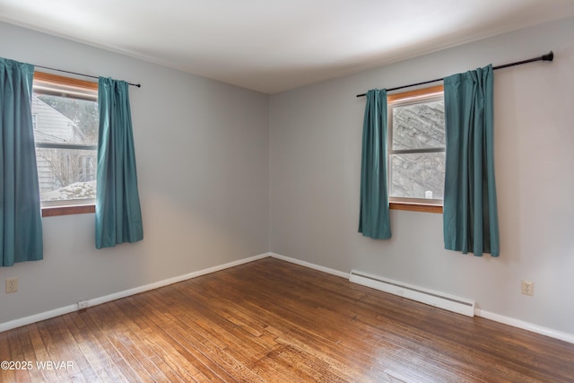 empty room featuring baseboard heating and dark hardwood / wood-style flooring