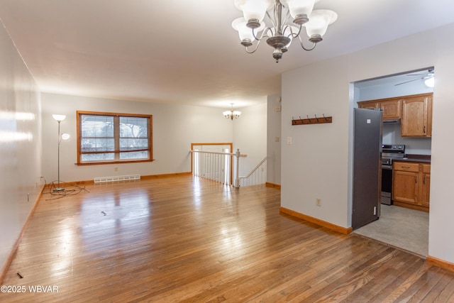 spare room featuring ceiling fan with notable chandelier and hardwood / wood-style flooring