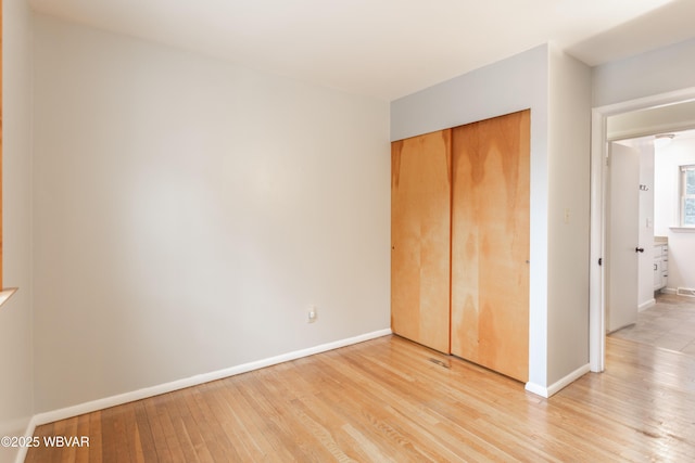 unfurnished bedroom featuring light wood-type flooring and a closet