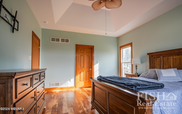 bedroom featuring a raised ceiling, light hardwood / wood-style flooring, and ceiling fan