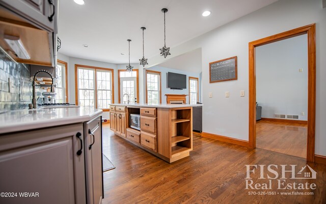 kitchen featuring dark hardwood / wood-style flooring, stainless steel microwave, a kitchen island, and a chandelier