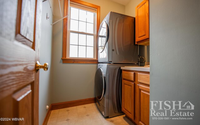 washroom with cabinets and stacked washer / drying machine