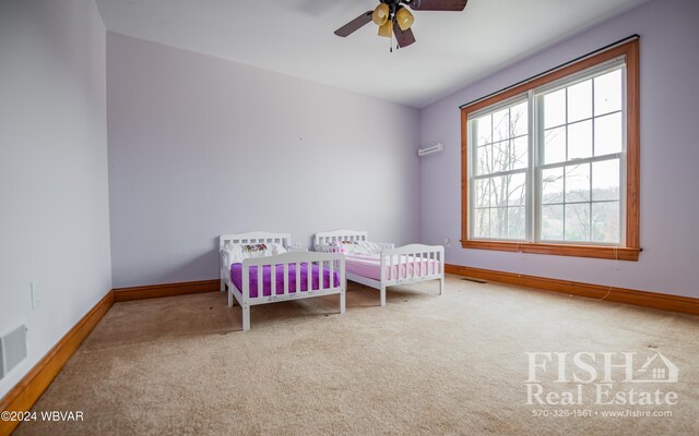 bedroom featuring ceiling fan, carpet floors, and a nursery area