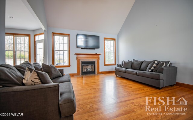 living room featuring plenty of natural light, vaulted ceiling, a tile fireplace, and light hardwood / wood-style flooring