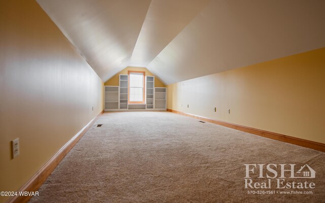 additional living space with carpet, built in features, and lofted ceiling