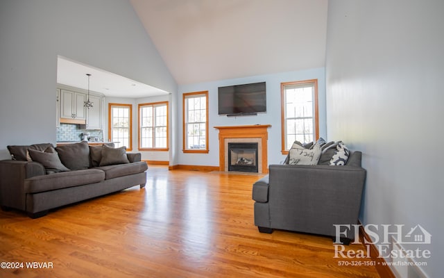 living room with light hardwood / wood-style floors, high vaulted ceiling, and a wealth of natural light