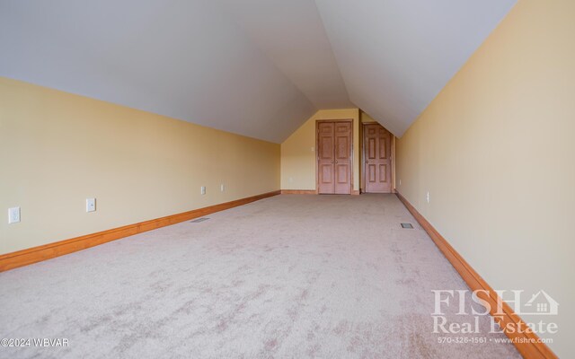 bonus room with carpet flooring and vaulted ceiling