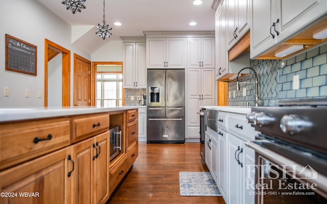 kitchen with dark wood-type flooring, white cabinetry, pendant lighting, and stainless steel appliances