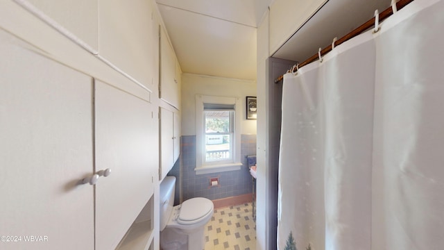 bathroom featuring tile patterned floors, curtained shower, toilet, and tile walls