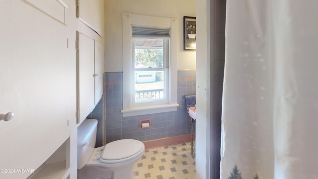 bathroom featuring tile patterned floors, toilet, and tile walls