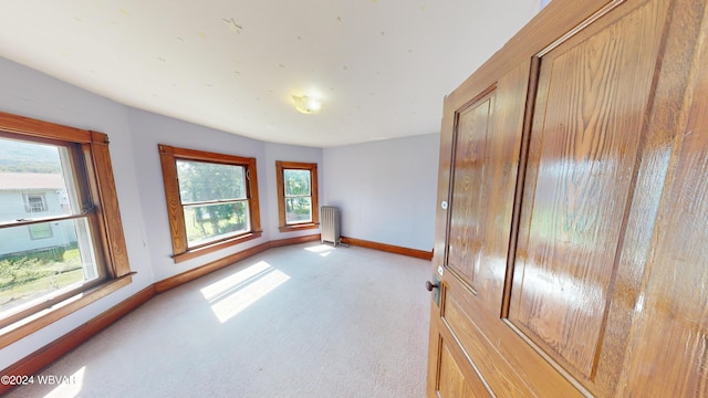 carpeted empty room featuring radiator heating unit