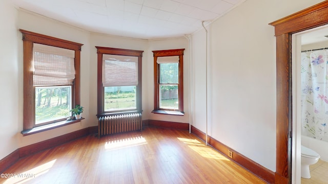 spare room with light hardwood / wood-style floors, radiator, and crown molding