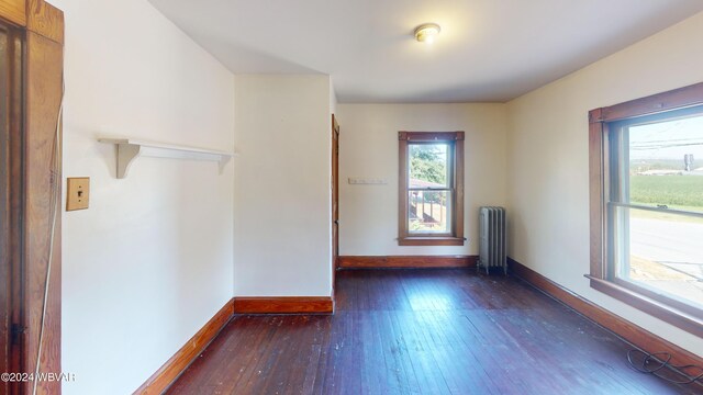 empty room featuring dark wood-type flooring and radiator