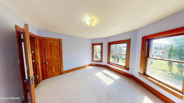 unfurnished room featuring plenty of natural light and light colored carpet