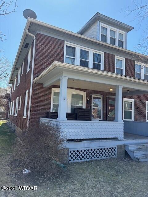 view of front of home with brick siding and covered porch
