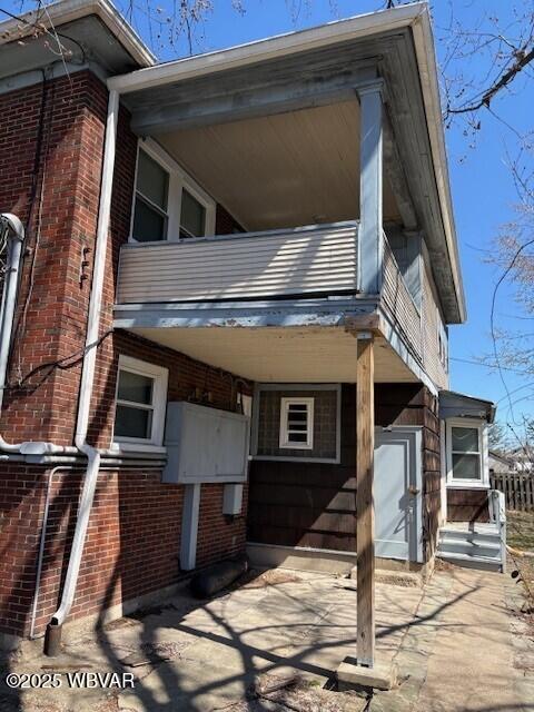 exterior space featuring brick siding and a balcony
