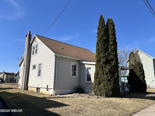 view of property exterior featuring a lawn, a chimney, and a shingled roof