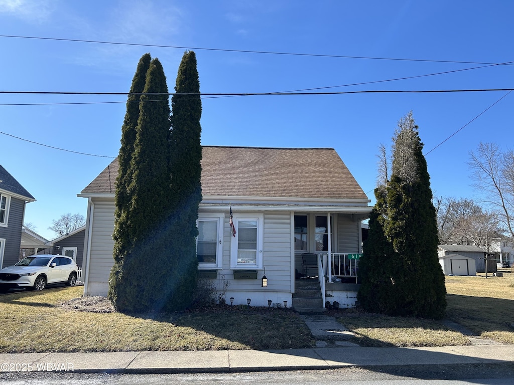 view of front of home with a porch, a front yard, and roof with shingles