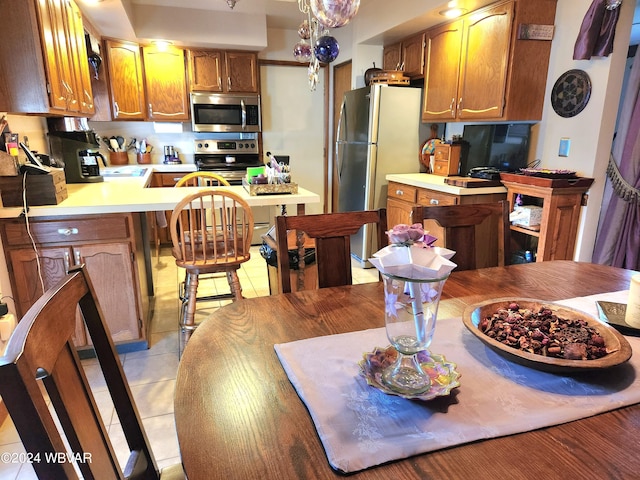 kitchen with kitchen peninsula, light tile patterned floors, and stainless steel appliances