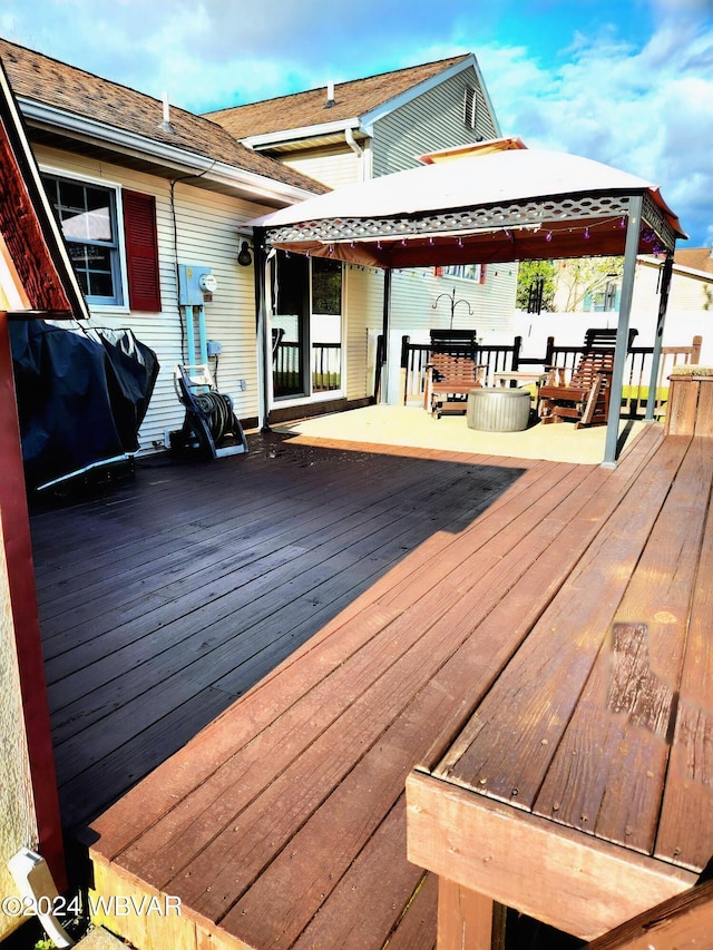 wooden deck with a gazebo, grilling area, and fence