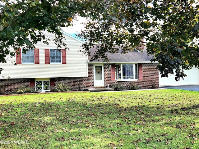 tri-level home featuring driveway, brick siding, and a front yard