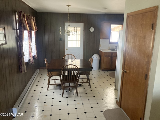 dining room featuring light floors, baseboard heating, a wealth of natural light, and an inviting chandelier