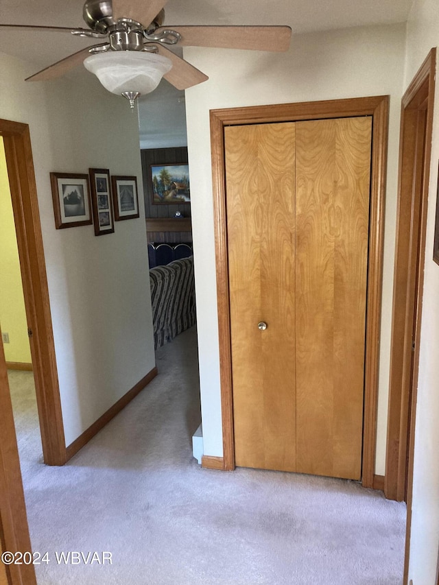 corridor featuring light colored carpet and baseboards